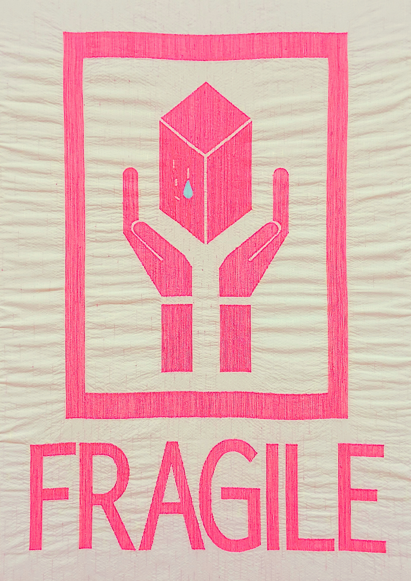 ファイバーアート作品《ワレモノ、あなたもわたしも》全体図。ピンク色の手が箱を支える「FRAGILE（割れ物注意）」のシンボルをモチーフに、壊れやすさや人の心の繊細さを糸で表現している。